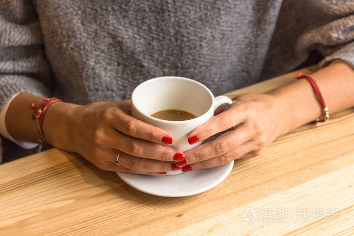 女性手中的白色咖啡杯. 用一杯热饮料温暖你的手. 在咖啡馆见面.