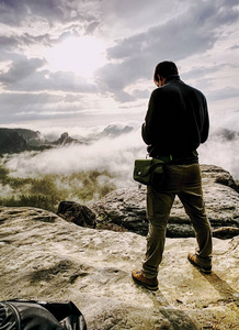 摄影师用数码相机拍摄秋天的照片,在雾蒙蒙的秋天景观上方的山峰上.
