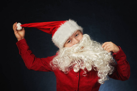 一个穿成圣诞老人的男孩在黑暗背景上的肖像