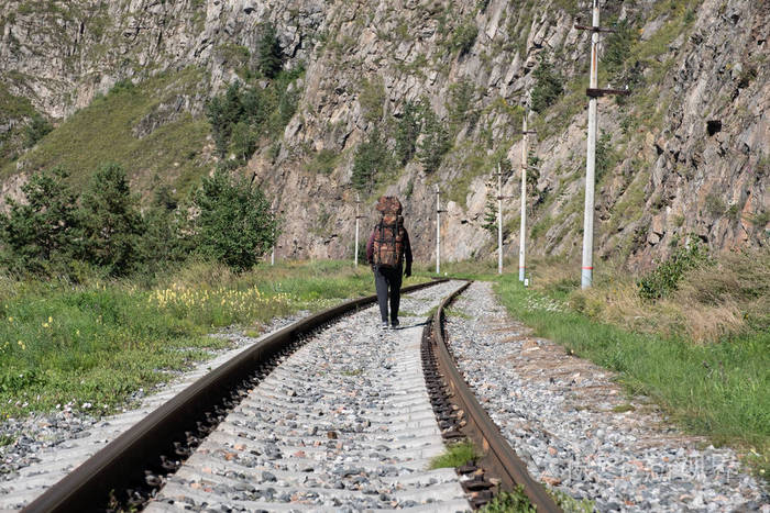 孤独的旅行者沿着铁路沿着山区行走.