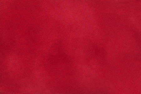 深红色哑光背景的绒面织物特写。 无缝葡萄酒皮革的天鹅绒质地。 感觉材料宏观。