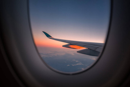 飞机的剪影翼在日出视图通过窗户。
