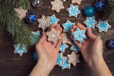 圣诞姜饼雪花饼干用女性的手装饰着糖霜。圣诞节和新年传统，寒假，自制糖果，节日食品