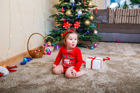 婴儿戴红帽的圣诞照片。新年假期和圣诞树