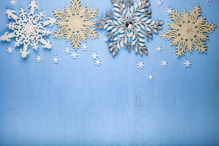 蓝色木制背景上的圣诞雪花。 银色雪花的边界。
