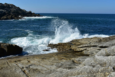 海浪撞击岩石。 野生海崖和碧水。 白色泡沫蓝天晴天。 加利西亚西班牙。