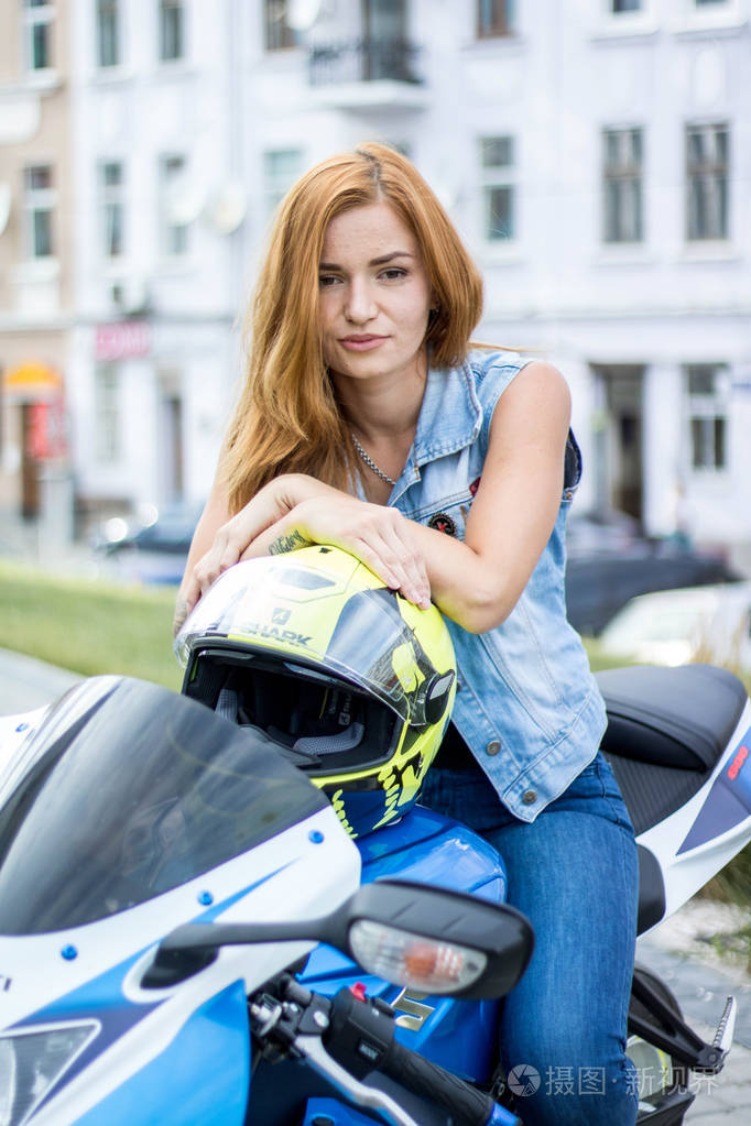 摩托车上的红头发女孩一辆摩托车铃木gsxr2011蓝色与白色自行车与帽子