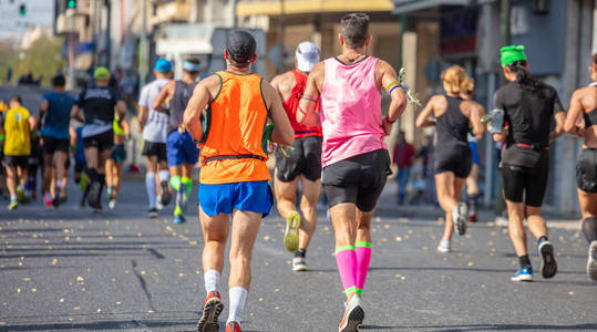 马拉松赛跑跑者团体在城市道路后景