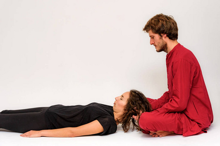 瑜伽姿势的照片在地板上进行两次伸展和在白色背景下放松。 男人在镜头前伸展女人。