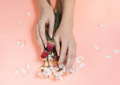 时尚艺术女性手中的花花和玫瑰，有着鲜明的对比。 美丽的照片女孩坐在桌子上，对比着粉红色的背景和彩色的阴影