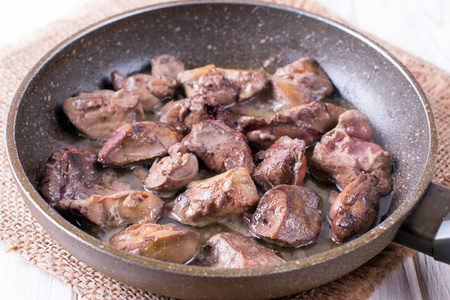 炸鸡肝在桌上的煎锅里照片