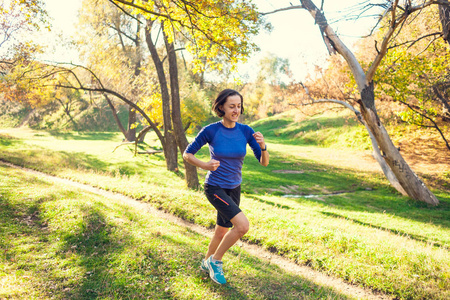 苗条的女人在大自然中训练. 森林里的运动. 黑发女人沿着一条土路跑.