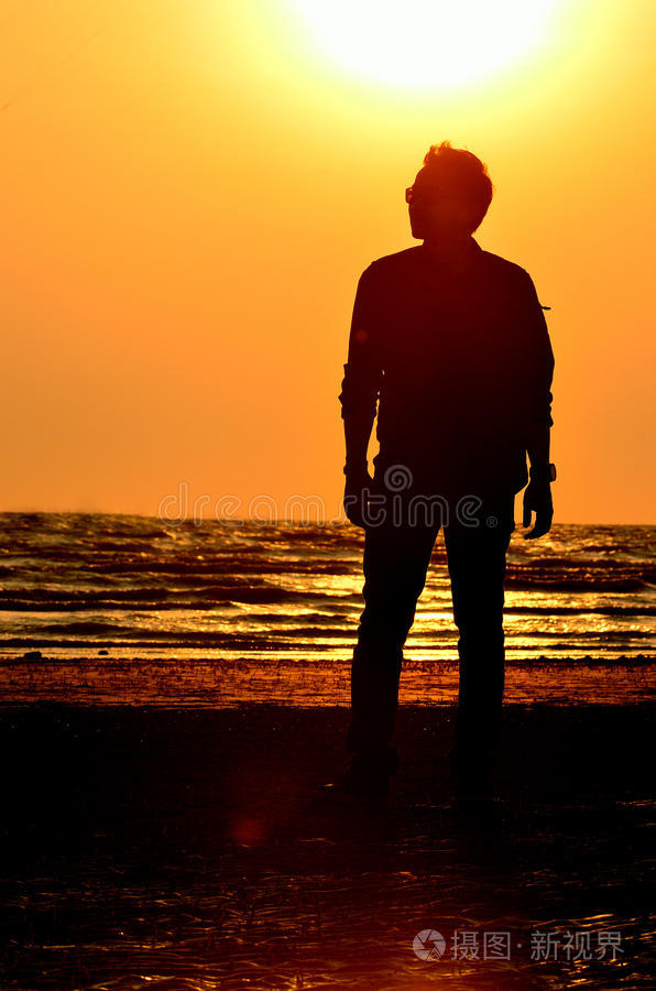 日落天空背景下的海滩上的男人剪影