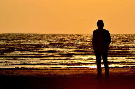 日落天空背景下的海滩上的男人剪影
