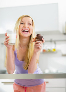 有牛奶和巧克力松饼的快乐年轻女人