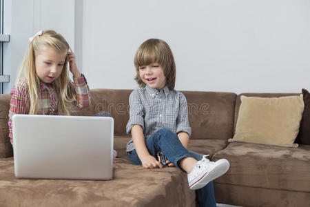 快乐男孩和妹妹在沙发上用笔记本电脑