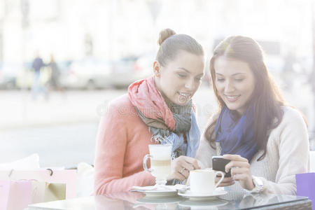 冬天快乐的女人在路边咖啡厅用手机