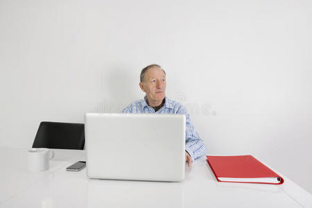 体贴的资深商人在办公桌旁使用笔记本电脑