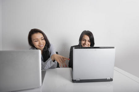 微笑的女商人在办公室办公桌旁用笔记本电脑