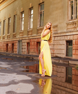 美丽的金发女子穿着黄色长裙在户外