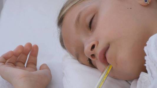 生病的孩子躺在病床上生病的孩子睡在温度计上受苦的女孩