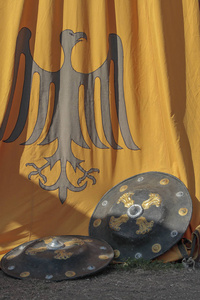 两个中世纪盾牌的前景斜靠在一个中世纪黄色军事帐篷的侧面