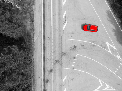 公路的鸟瞰图。 带有移动红色汽车的乡村道路的鸟瞰图。 汽车经过。 空中道路。 空中观景飞行。 用无人机从上面捕获。 黑白的