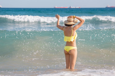穿着泳衣的年轻女性游客在地中海的波浪状水域享受乐趣，海上风暴天气的概念