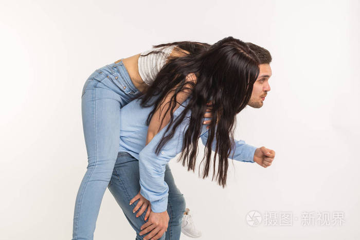 一对摆姿势在白色背景有趣的男人抱女人在他的背上