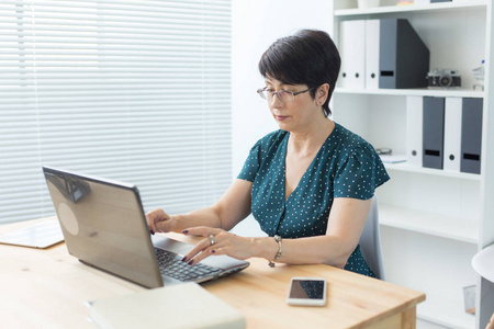 商业技术和人的概念中年妇女在办公室工作, 使用笔记本电脑