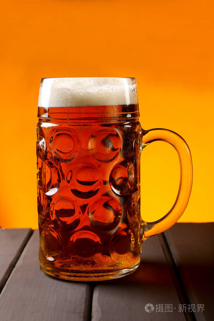 一个杯子,一个木桌上的啤酒杯和一个橙色的背景