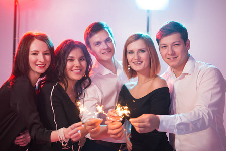 一群开朗的青年男女拿着火花.新年,节假日和派对理念照片