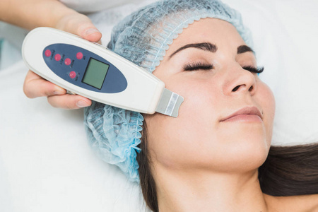 美容师在美容院为一名年轻女子做超声波洗脸手术照片