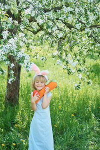 可爱的有趣女孩，在花园里有复活节彩蛋和兔子耳朵。 复活节的概念。 复活节猎蛋的笑孩子。 公园里的孩子有大胡萝卜春天的概念
