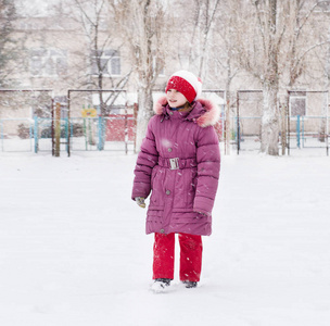 可爱的小女孩在雪地公园散步，冬天