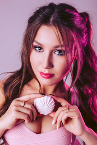 一个粉红紫色背景的漂亮迷人的女人手里拿着棉花糖