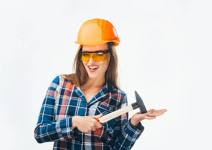 年轻快乐有魅力的女孩在建造橙色头盔和眼镜与锤子。完全孤立的工作室图片从情感手工艺妇女。