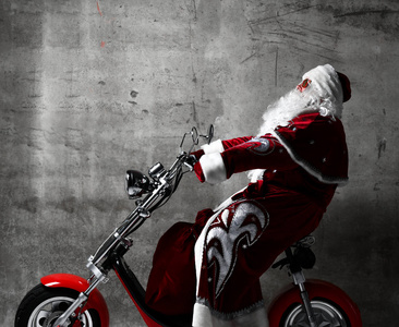 圣诞老人骑电动摩托车摩托车滑板车与袋子充满了礼物和文字复制空间