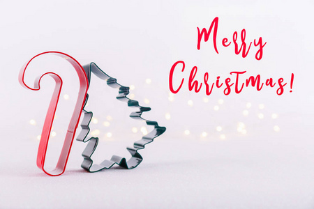糖果和圣诞树饼干切割机在白色闪闪发光的背景与博克灯。 节日圣诞卡背景。 水平的。 假日措辞