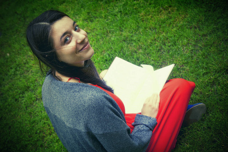 美丽的年轻女子在草地上拿着书。 其他知识科学教育概念