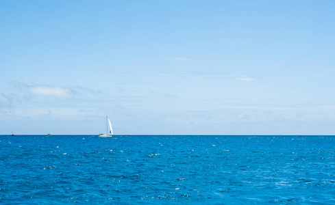 远在天边的小游艇，白色的帆，平静的海洋，蓝天