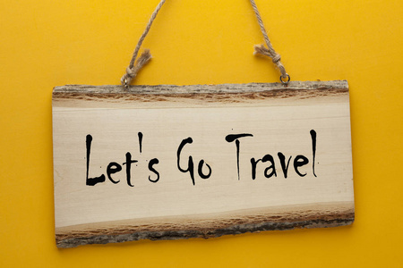 s Go Travel text with wooden sign hanging on a rope on yellow ba