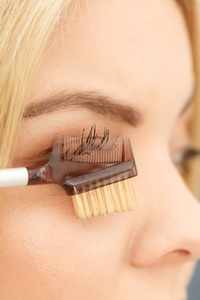 特写女人做她的化妆准备睫毛使用刷子工具刷睫毛。