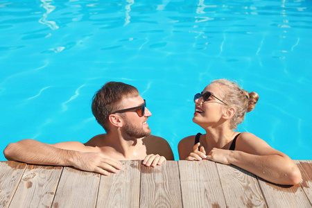 度假村游泳池里的一对幸福的年轻夫妇