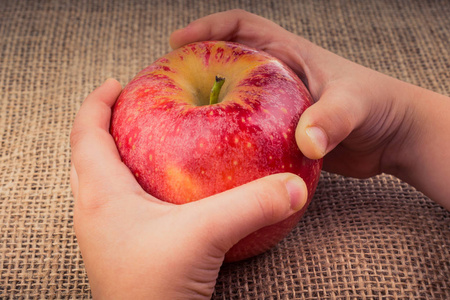 手拿着一个新鲜的红苹果在画布上