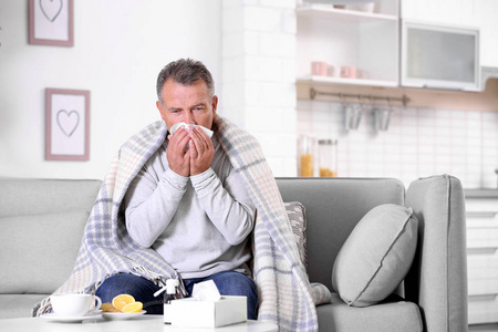 男人在家里沙发上咳嗽和感冒。 文本空间