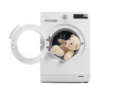 白色背景泰迪熊的现代洗衣机。 洗衣日