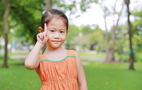 微笑的亚洲小女孩在自然公园的肖像与看相机。