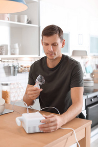 男人在厨房的桌子上用哮喘机图片
