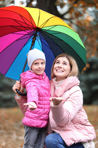 在雨天秋天公园带伞的母女